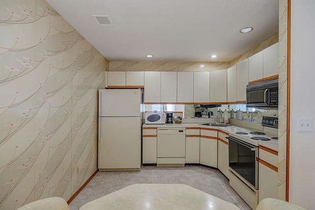 kitchen with white cabinets, white appliances, and sink