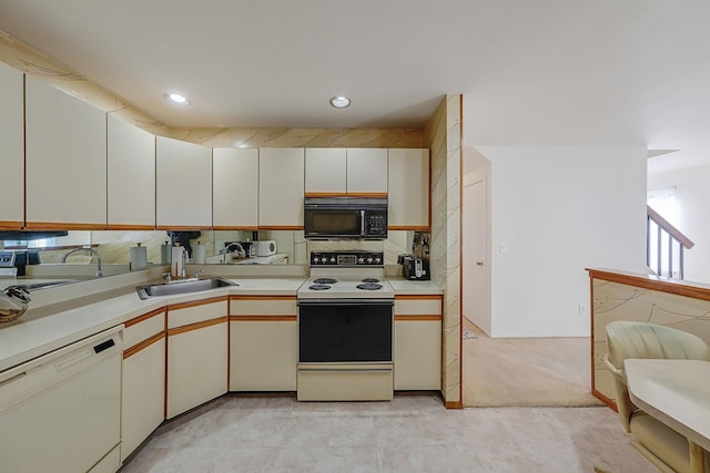 kitchen featuring white dishwasher, sink, range with electric stovetop, light colored carpet, and white cabinetry