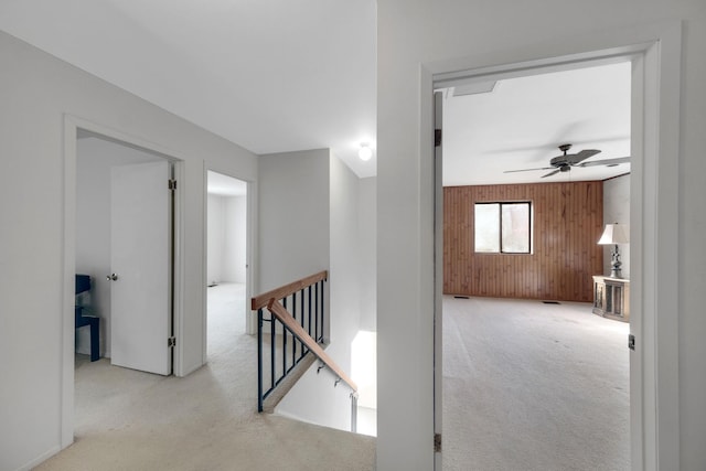 hallway with light colored carpet and wooden walls