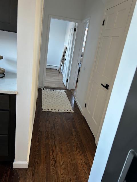 corridor featuring dark wood-type flooring and a baseboard radiator