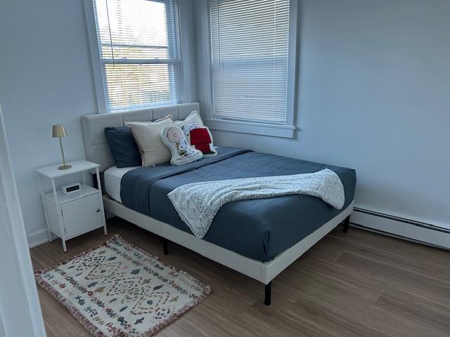 bedroom with hardwood / wood-style flooring and a baseboard heating unit