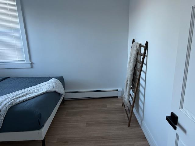 bedroom featuring a baseboard radiator and dark hardwood / wood-style floors