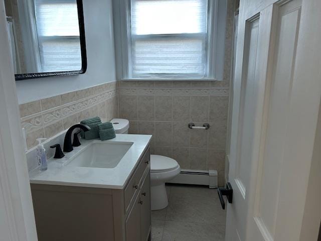 bathroom with a wealth of natural light, vanity, a baseboard heating unit, and toilet