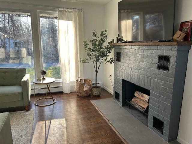 sitting room with a fireplace, hardwood / wood-style floors, and baseboard heating