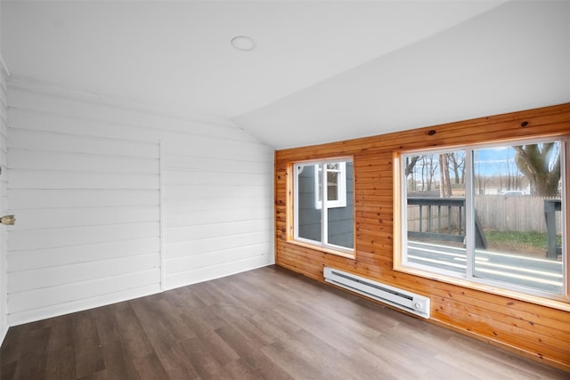 spare room featuring wood-type flooring, lofted ceiling, wooden walls, and a baseboard radiator