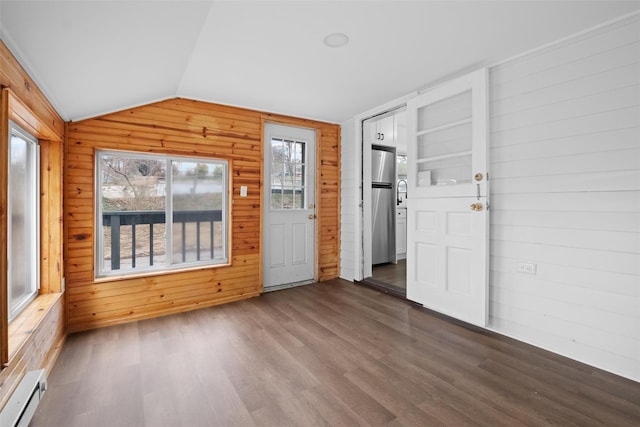 interior space with vaulted ceiling, baseboard heating, dark wood-type flooring, and wood walls