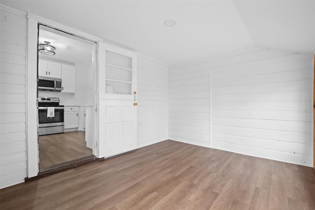 spare room featuring wooden walls, hardwood / wood-style flooring, built in features, and lofted ceiling