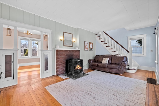 living room featuring light wood-type flooring, an inviting chandelier, and a wood stove