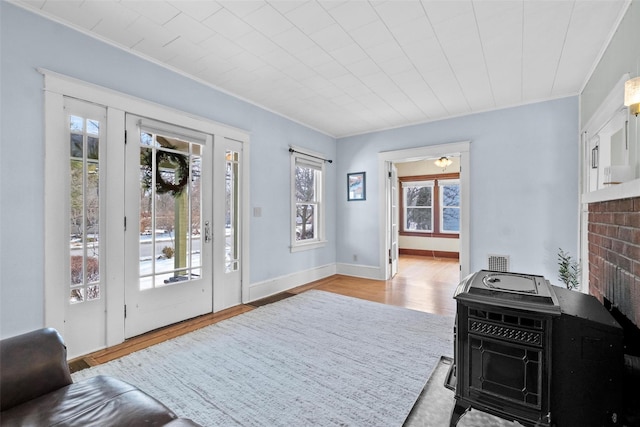 interior space with a wood stove, crown molding, and light wood-type flooring