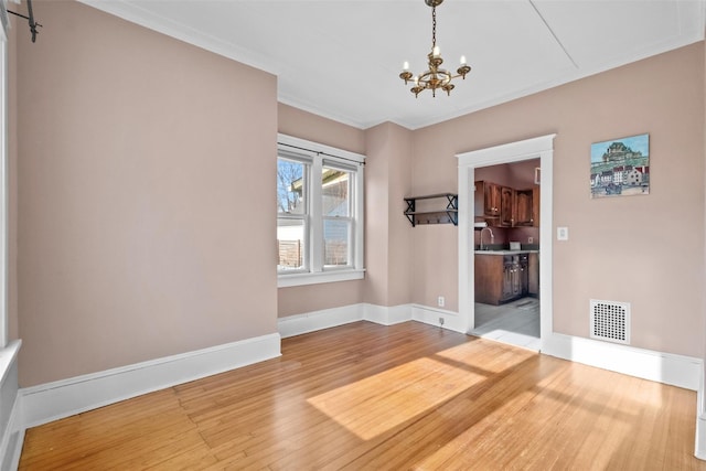 unfurnished room featuring hardwood / wood-style flooring, an inviting chandelier, ornamental molding, and sink