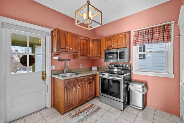 kitchen featuring sink, a notable chandelier, pendant lighting, light tile patterned flooring, and appliances with stainless steel finishes