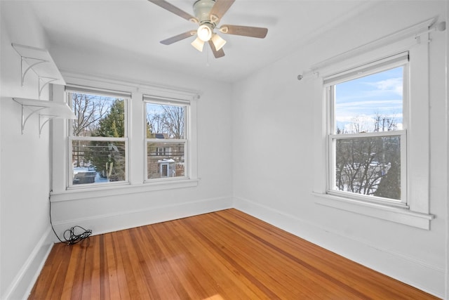 empty room with ceiling fan, a healthy amount of sunlight, and hardwood / wood-style flooring