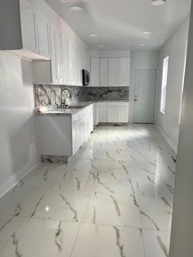 kitchen featuring tasteful backsplash, white cabinetry, and sink