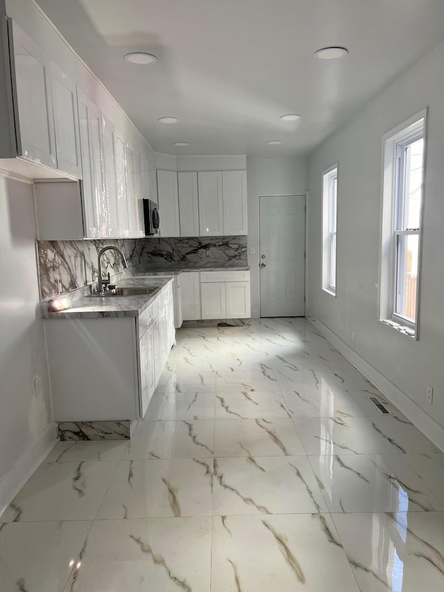 kitchen with white cabinets, backsplash, and sink