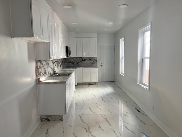 kitchen featuring decorative backsplash, sink, and white cabinets