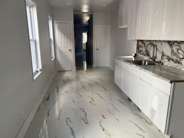 kitchen with white cabinets, plenty of natural light, and sink