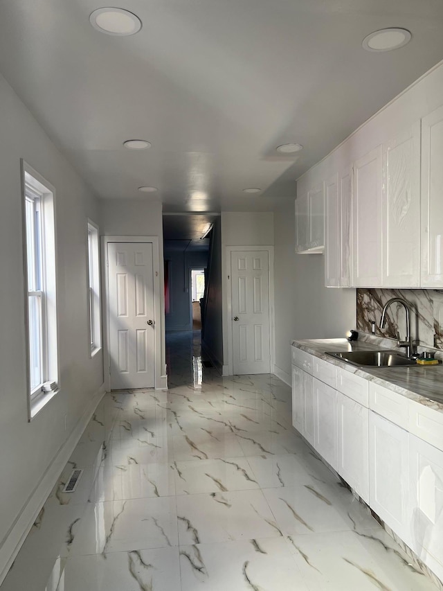 kitchen with white cabinets, decorative backsplash, and sink