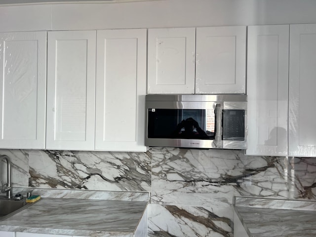 interior details featuring white cabinetry, sink, and a brick fireplace