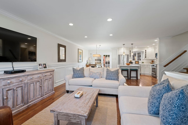 living room with recessed lighting, wood finished floors, stairway, wainscoting, and crown molding