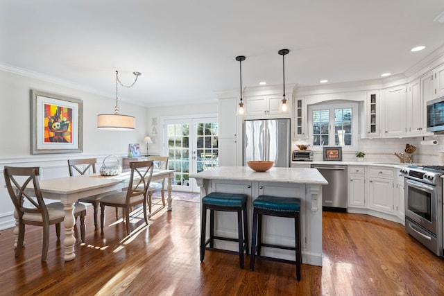 kitchen featuring appliances with stainless steel finishes, a kitchen island, glass insert cabinets, and white cabinetry