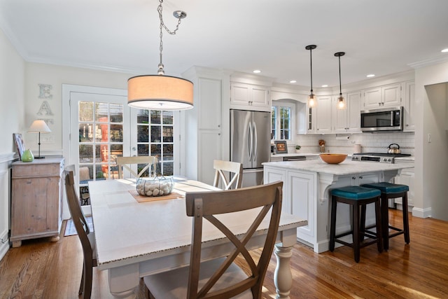 dining room with dark wood-style floors, ornamental molding, and recessed lighting