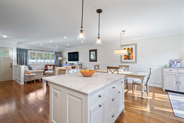 kitchen featuring light stone counters, hanging light fixtures, open floor plan, white cabinetry, and a kitchen island