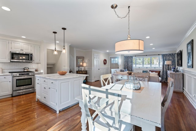 dining space featuring a wainscoted wall, crown molding, dark wood-style flooring, and recessed lighting