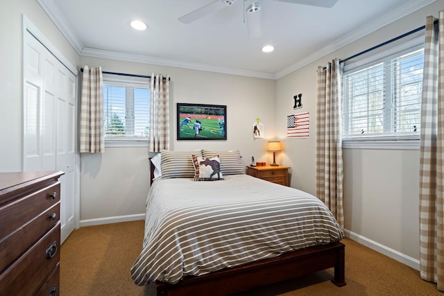 carpeted bedroom with ceiling fan, a closet, baseboards, and crown molding