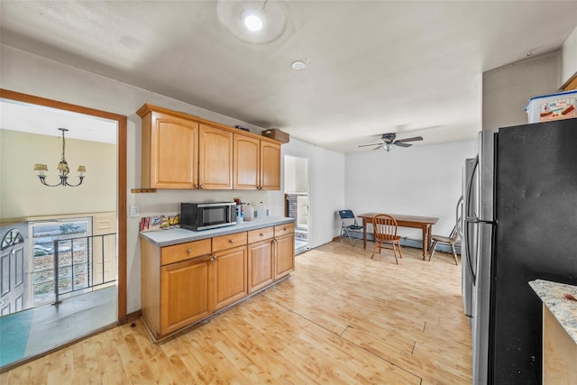 kitchen featuring ceiling fan with notable chandelier, appliances with stainless steel finishes, light wood-type flooring, and pendant lighting