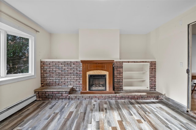 unfurnished living room with hardwood / wood-style floors, built in shelves, a brick fireplace, and a baseboard heating unit