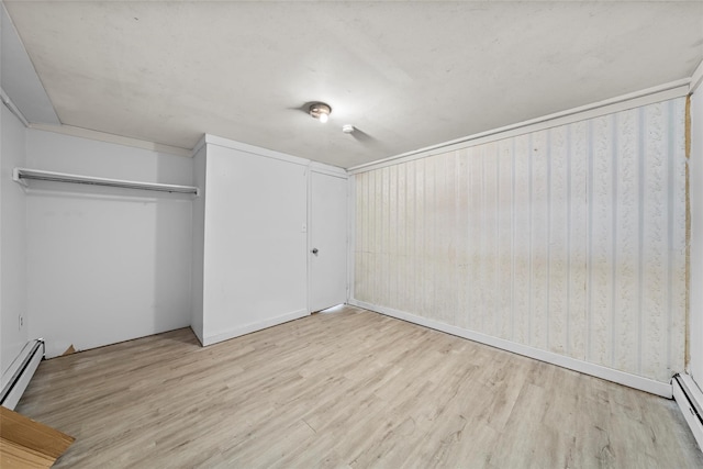 unfurnished bedroom featuring a closet, a baseboard radiator, and light hardwood / wood-style flooring