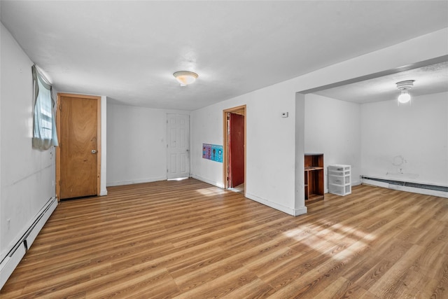 unfurnished room with baseboard heating and wood-type flooring