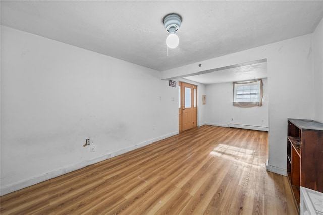 unfurnished living room featuring light hardwood / wood-style floors, a textured ceiling, and a baseboard heating unit