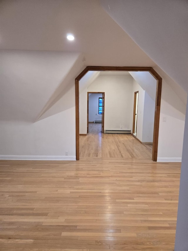 additional living space featuring lofted ceiling, baseboard heating, and light wood-type flooring