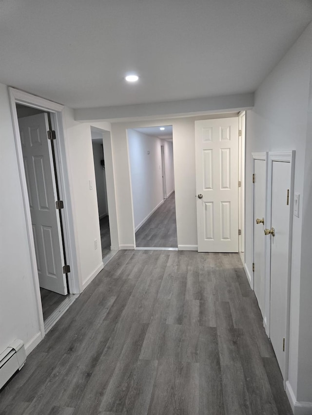 hallway featuring a baseboard heating unit and dark wood-type flooring