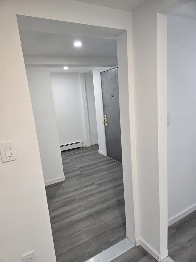 hall with a baseboard heating unit and dark hardwood / wood-style floors