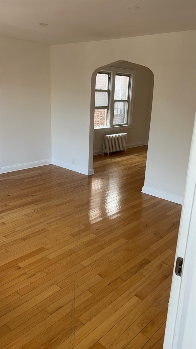 spare room featuring radiator and light hardwood / wood-style floors