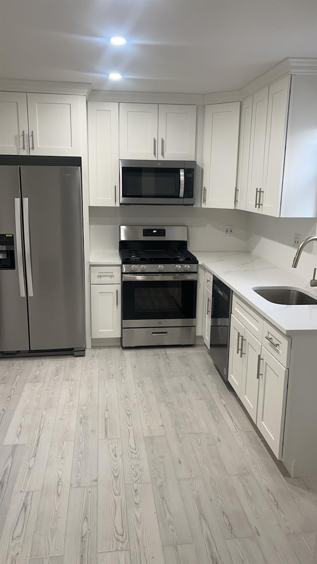 kitchen with white cabinetry, appliances with stainless steel finishes, sink, and light hardwood / wood-style flooring