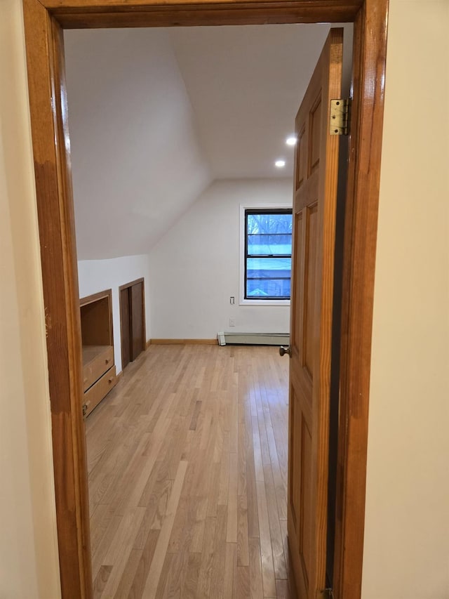 additional living space featuring lofted ceiling, baseboard heating, and light hardwood / wood-style flooring