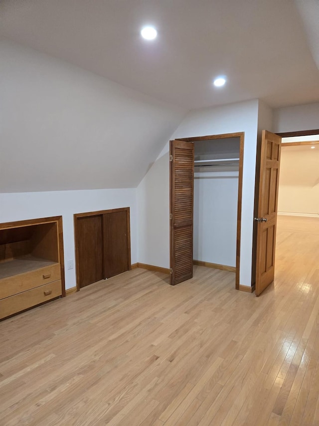 additional living space featuring vaulted ceiling and light hardwood / wood-style floors