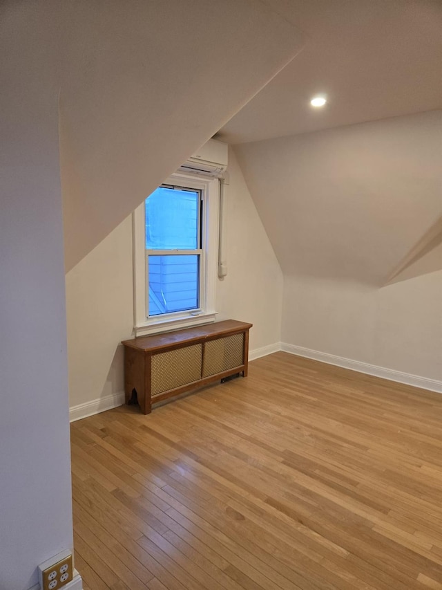 bonus room featuring lofted ceiling, radiator heating unit, and light hardwood / wood-style flooring