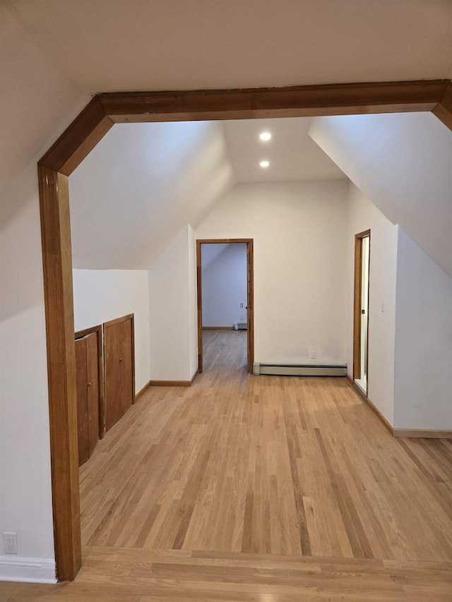 additional living space with baseboard heating, lofted ceiling, and light wood-type flooring