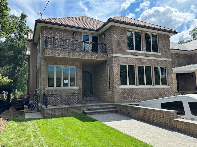 view of front of home with a balcony and a front lawn