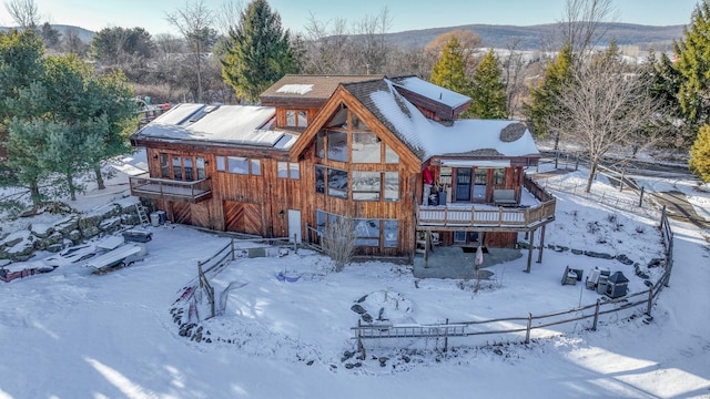 snow covered back of property featuring a deck with mountain view