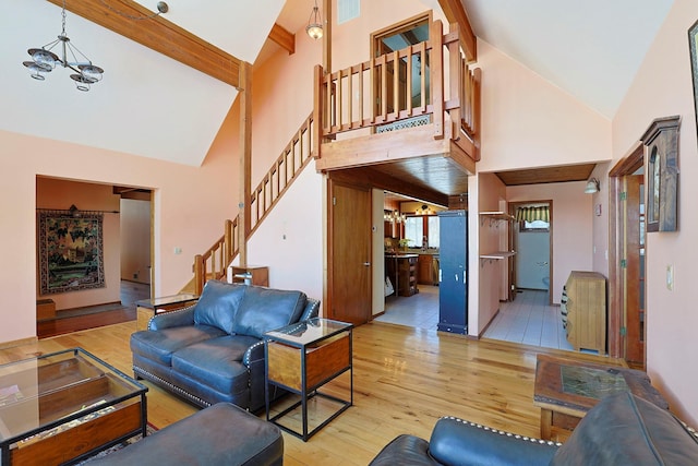 living room with beam ceiling, high vaulted ceiling, a chandelier, and light hardwood / wood-style floors