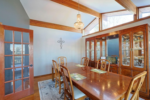 dining room with hardwood / wood-style flooring, vaulted ceiling with beams, and a notable chandelier