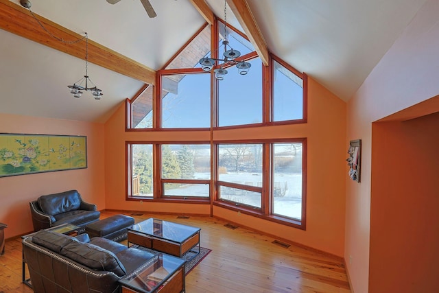 living room with beamed ceiling, high vaulted ceiling, an inviting chandelier, and light hardwood / wood-style floors