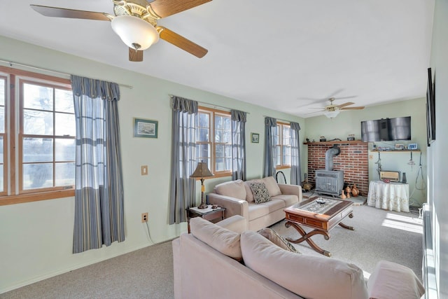 carpeted living room featuring a wood stove, a wealth of natural light, and ceiling fan