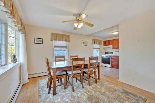 dining room with light hardwood / wood-style floors, baseboard heating, and a healthy amount of sunlight