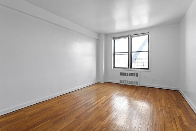 empty room featuring radiator heating unit and hardwood / wood-style flooring